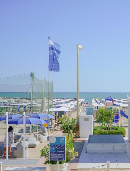 Spiaggia con ombrelloni, mare e giochi per bambini.