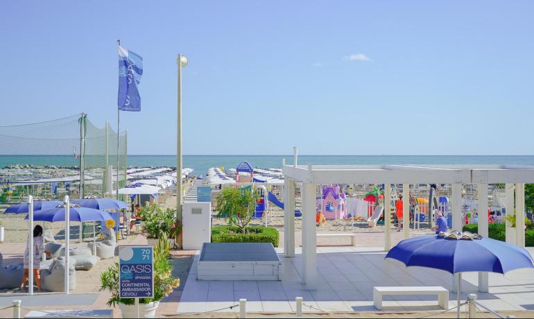 Spiaggia con ombrelloni, mare e giochi per bambini.