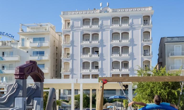 Parco giochi sulla spiaggia con hotel sullo sfondo.