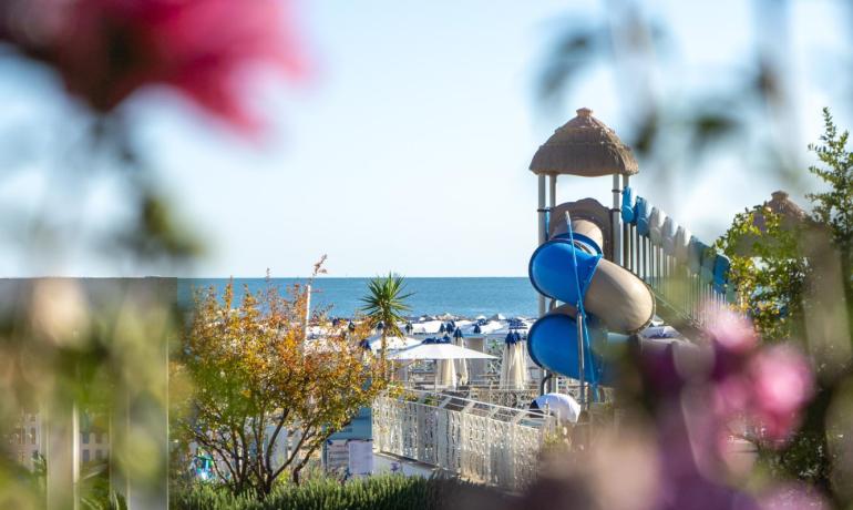 Vista sul mare con scivolo e tavolo da ping pong tra fiori.