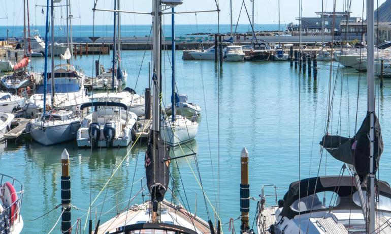 Barche a vela ormeggiate in un porto con cielo sereno.