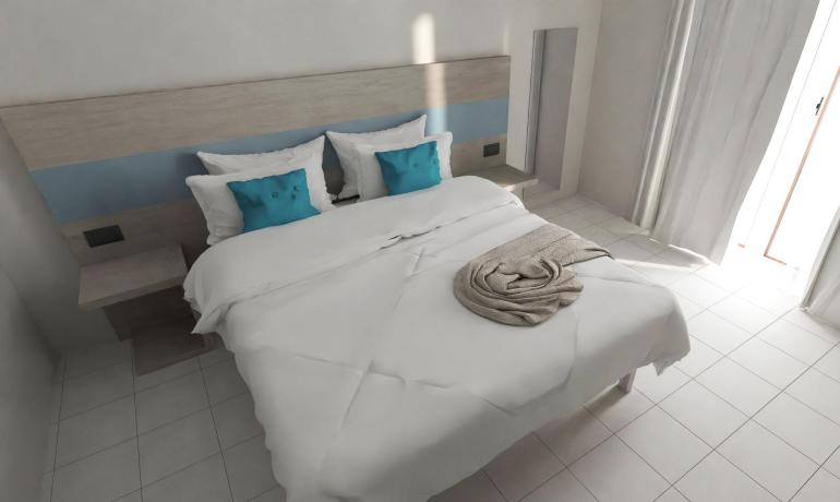 Camera moderna con letto bianco e cuscini blu.
