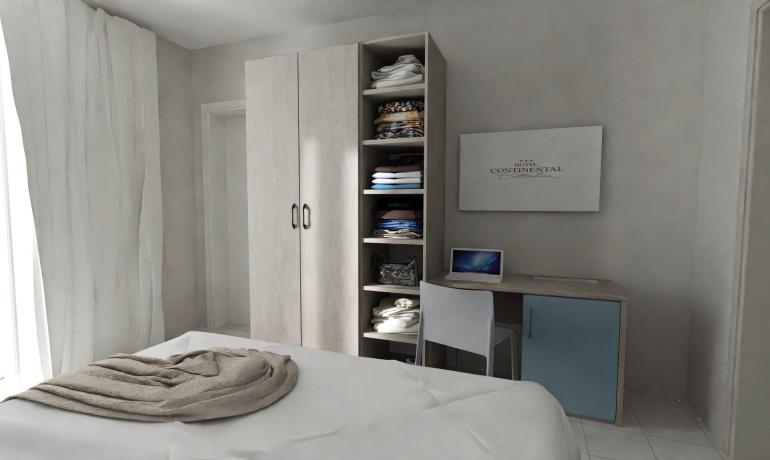 Camera d'albergo con armadio, scrivania e letto.