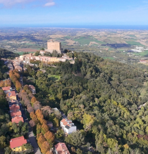 Castello su collina verde, villaggio pittoresco, paesaggio mozzafiato con cielo azzurro.