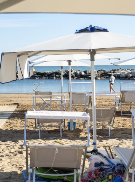Spiaggia tranquilla, sedie vuote, ombrelloni aperti, mare calmo, atmosfera serena e rilassante.
