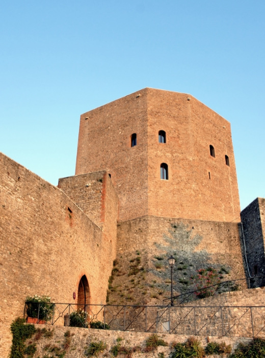 Torre medievale imponente, mura antiche, atmosfera storica al tramonto, silenzio e mistero.