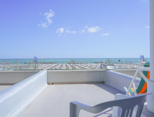 Vista mare serena, cielo blu, spiaggia ordinata, atmosfera rilassante e vacanziera.