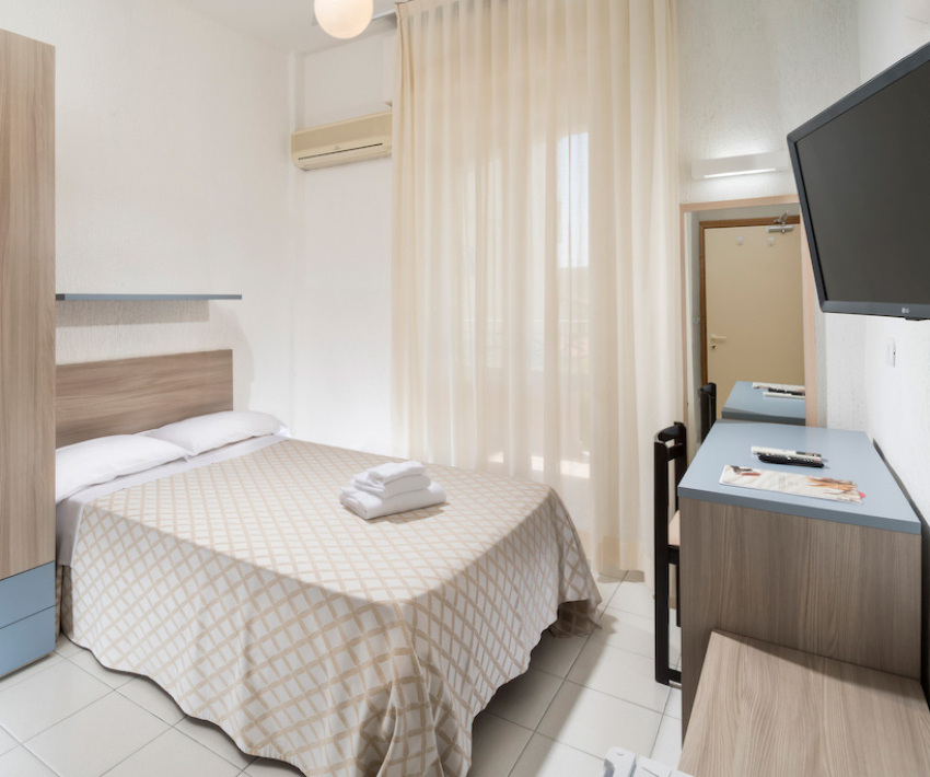 Camera moderna con letto matrimoniale, TV a parete e armadio in legno.