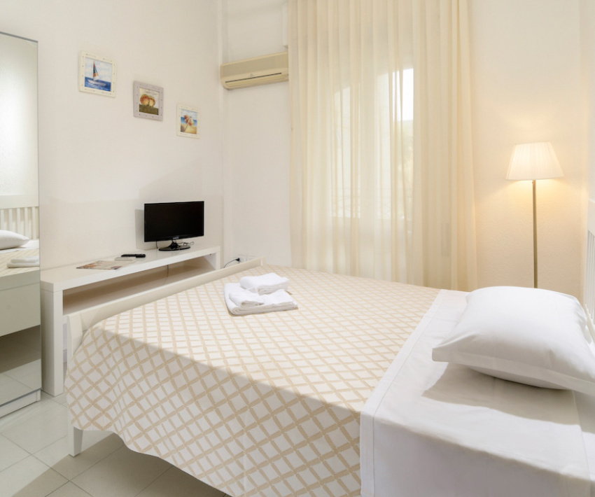 Camera moderna con letto matrimoniale, TV, specchio e illuminazione soffusa.