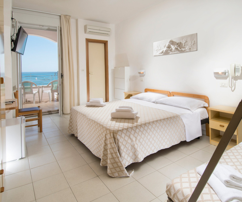 Vista dal balcone su una spiaggia affollata e mare azzurro.