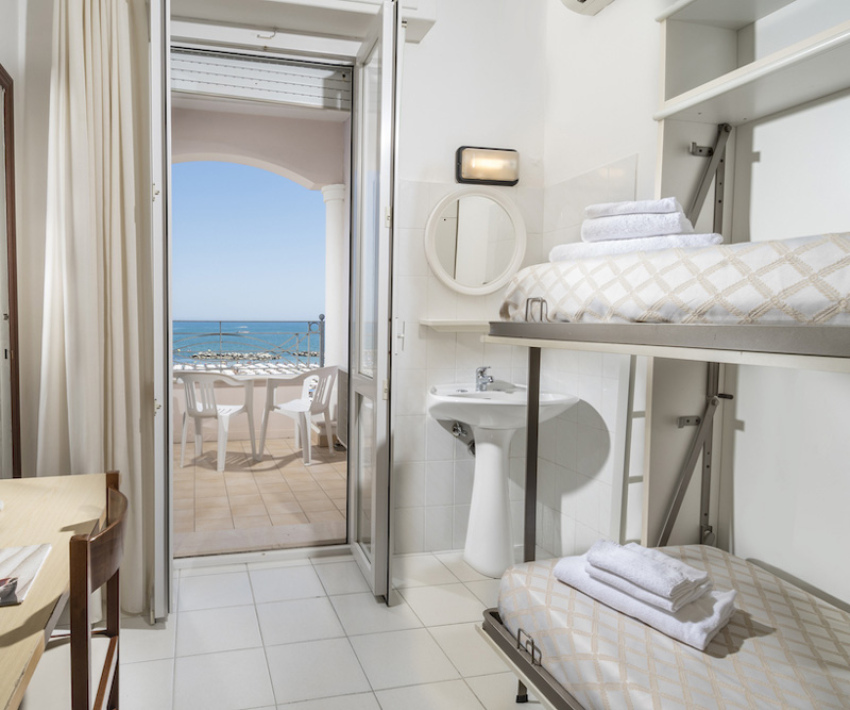 Camera con letti a castello, vista mare, balcone e TV.
